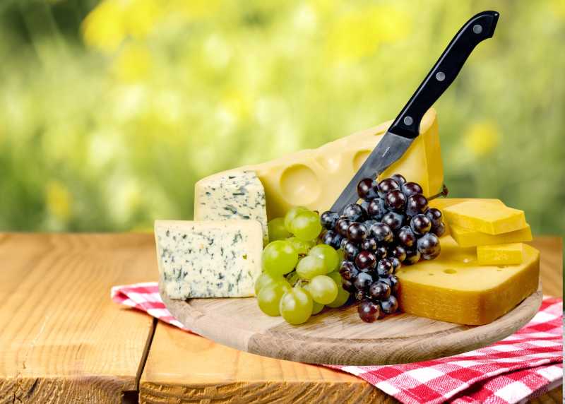 木板餐布上奶酪葡萄与刀具