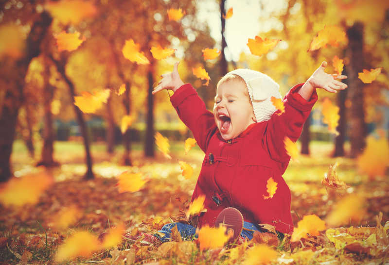 坐在秋天落叶里的小女孩