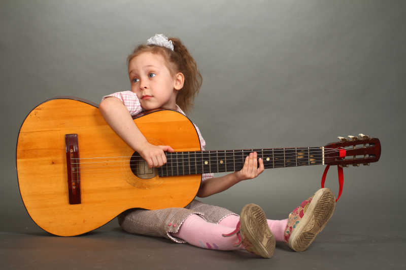 弹吉他的美丽的小女孩