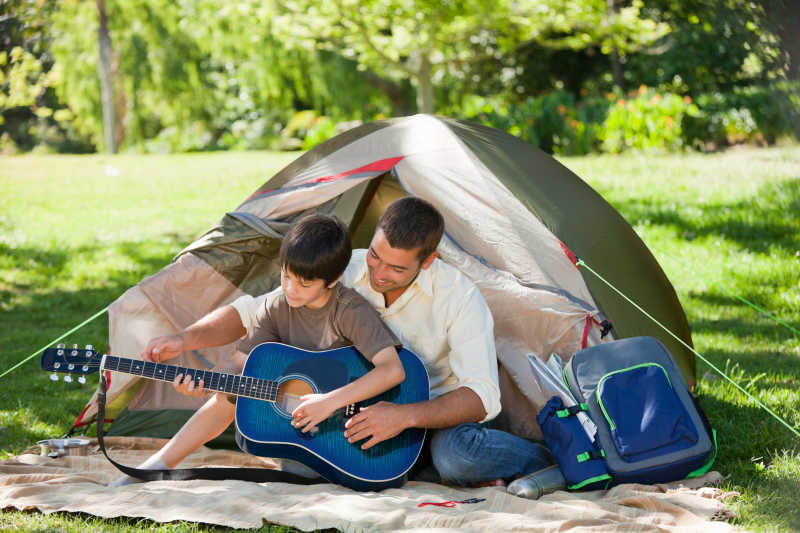 帐篷外边的父亲教儿子弹吉他