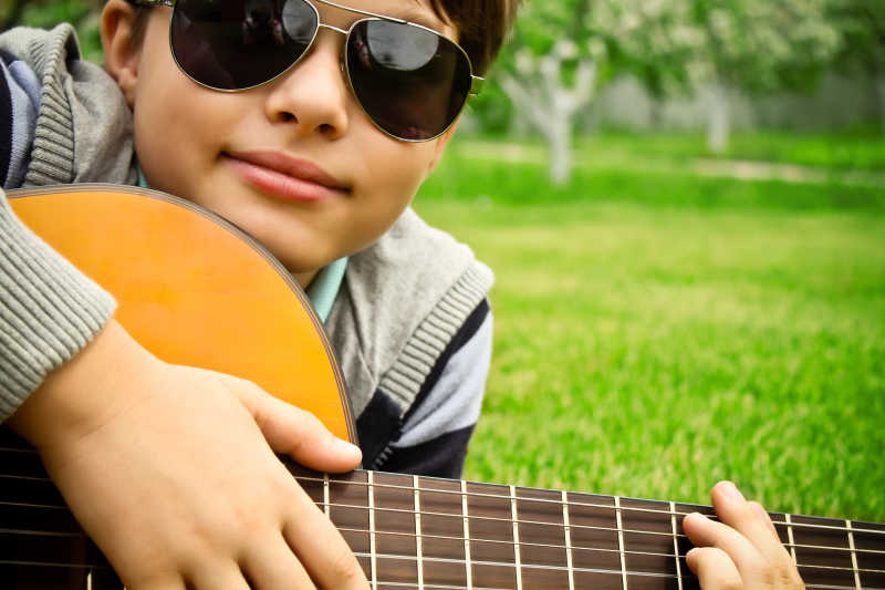 弹吉他的戴着墨镜的男孩特写