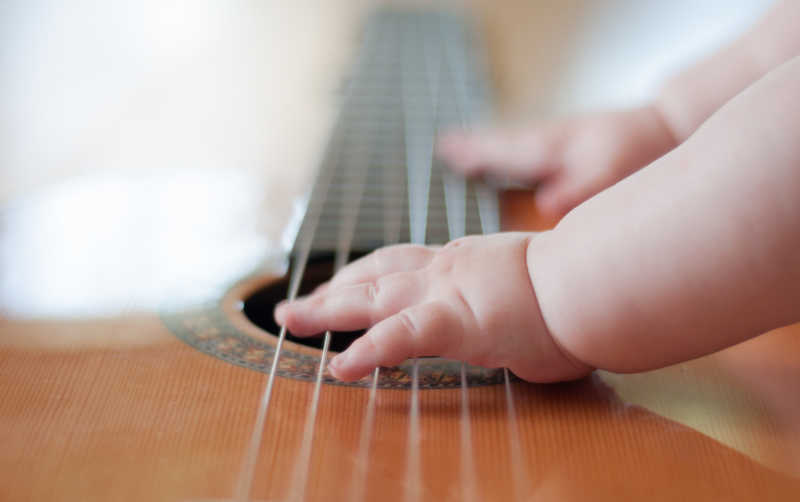 婴儿手放在吉他弦上特写