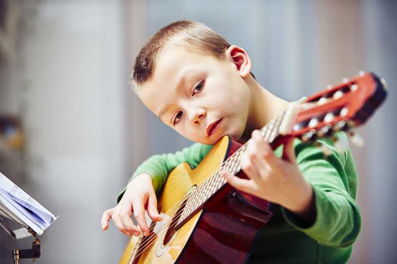 弹吉他的认真的小男孩