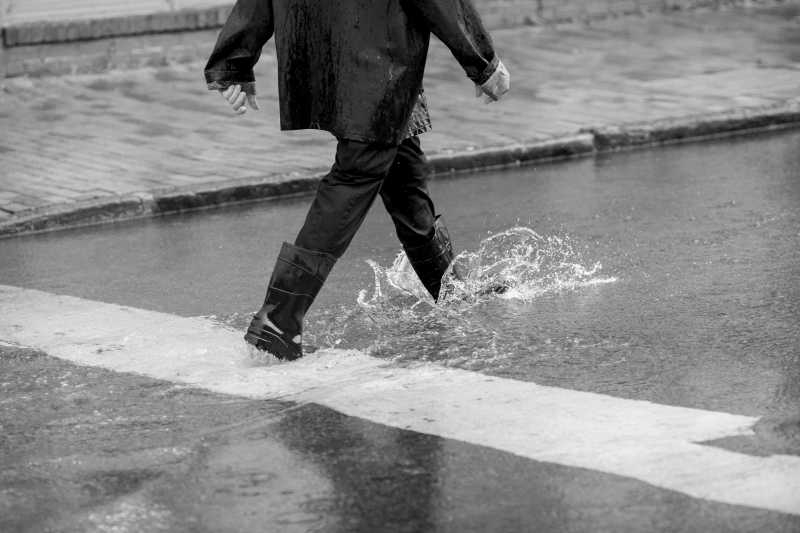 下雨天穿着雨靴走在积水的道路上