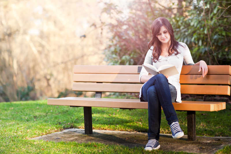 坐在公园长椅上的看书的大学生