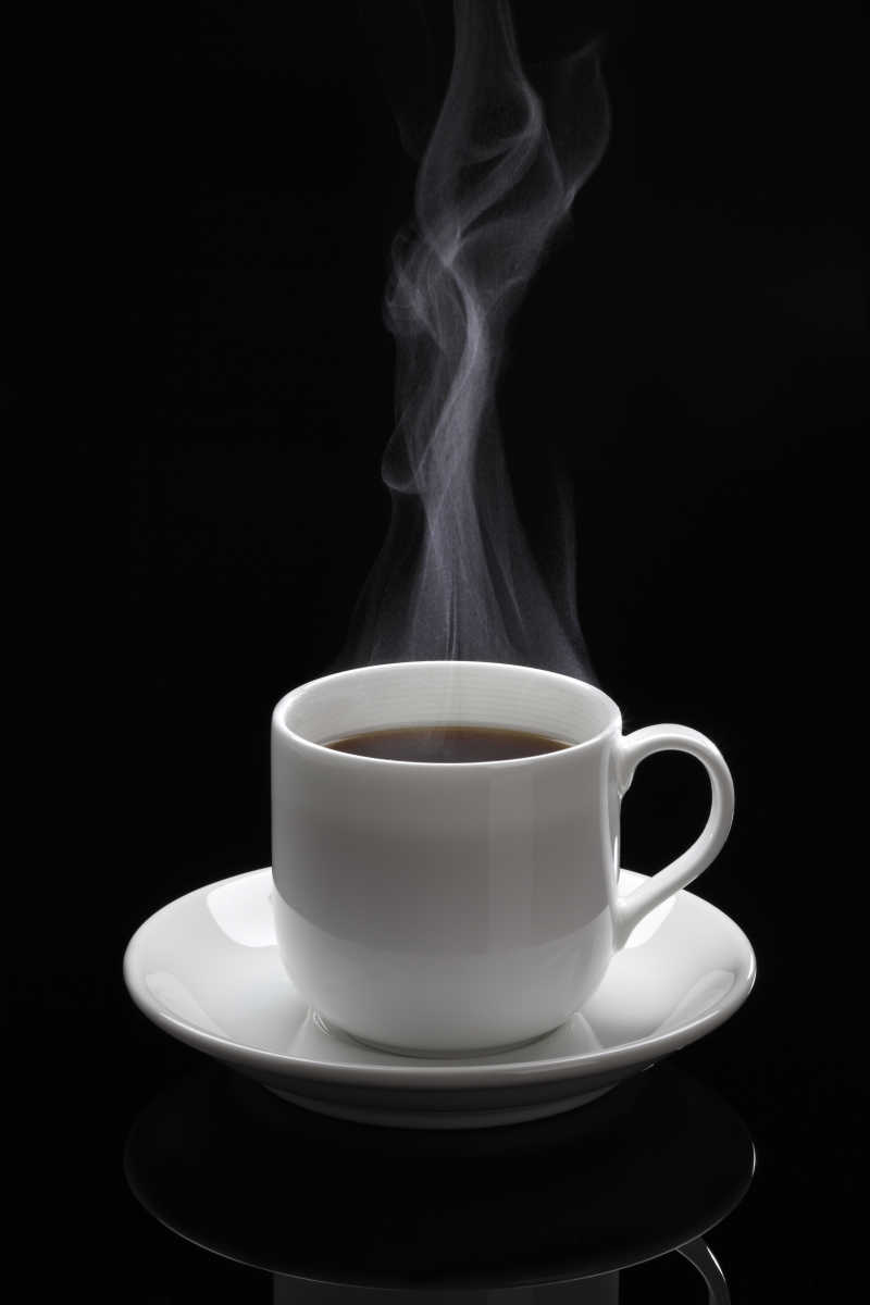 黑色背景下的一杯带杯托的热咖啡