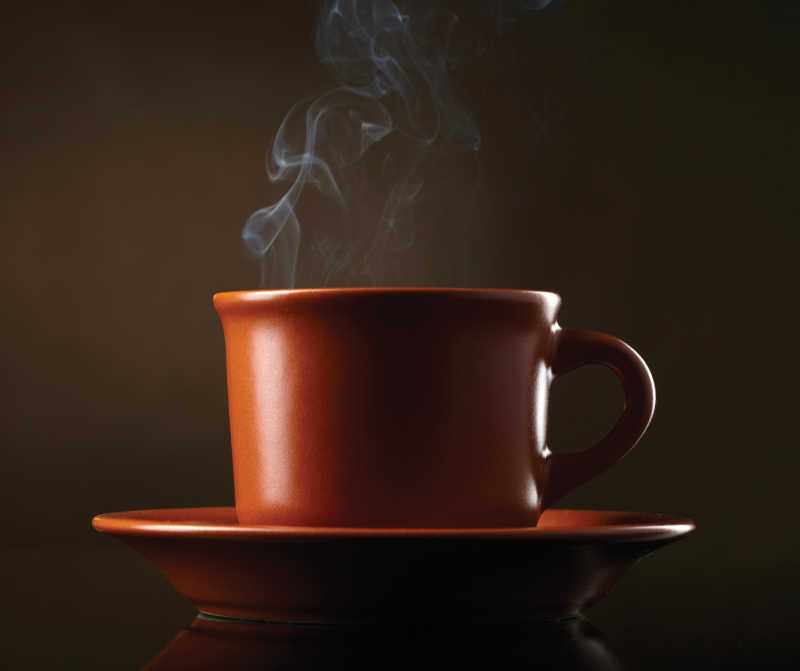 棕色背景下中式茶杯里的热气腾腾的饮料