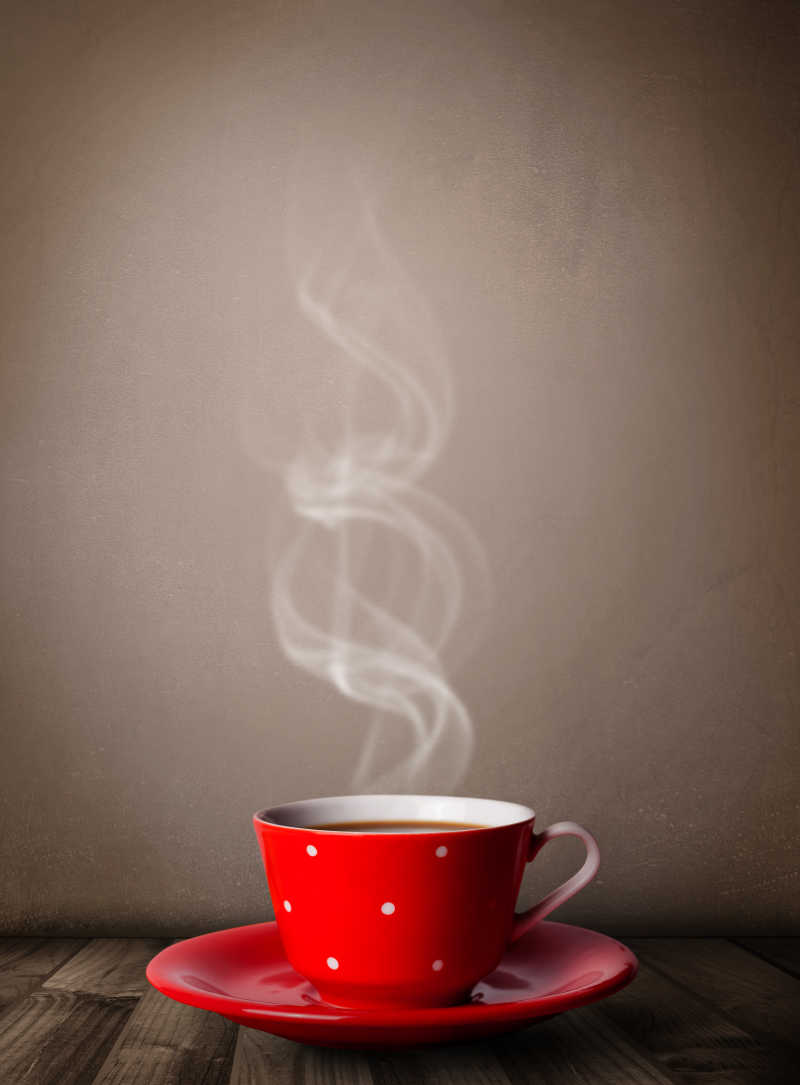 灰色背景下木桌上的一杯红色杯子盛好的热咖啡