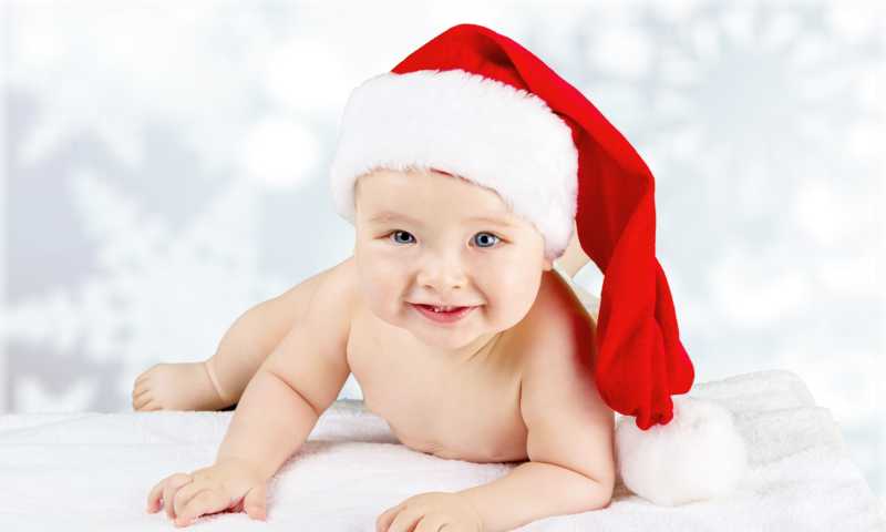 雪花背景上的戴着圣诞帽的婴儿