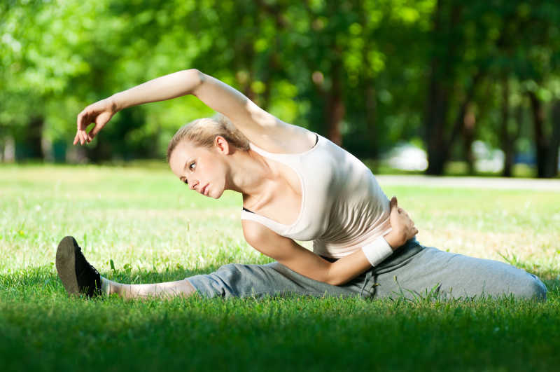 女子在公园的草坪上做伸展运动