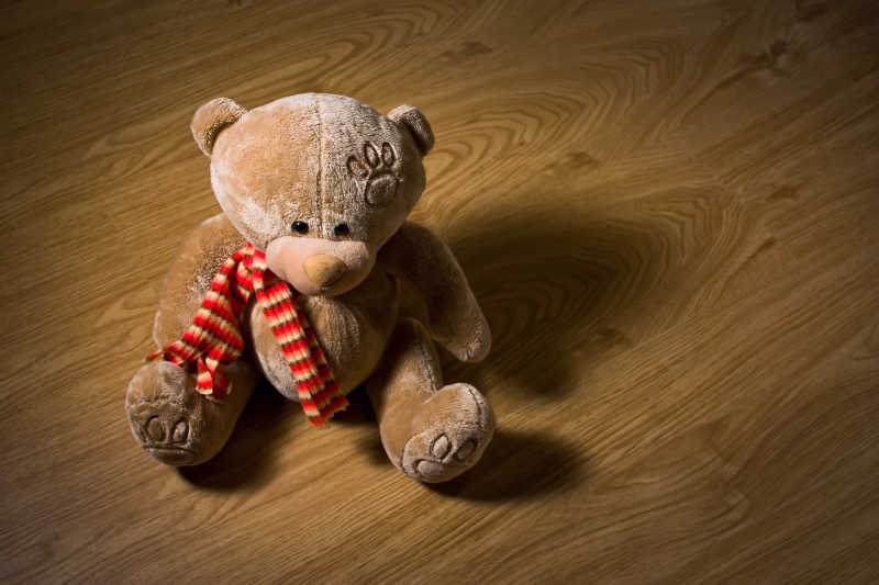 坐在木地板上的孤独的泰迪熊