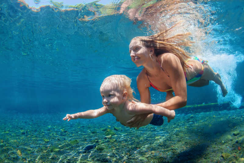 母亲带着孩子在清澈的海水里潜水