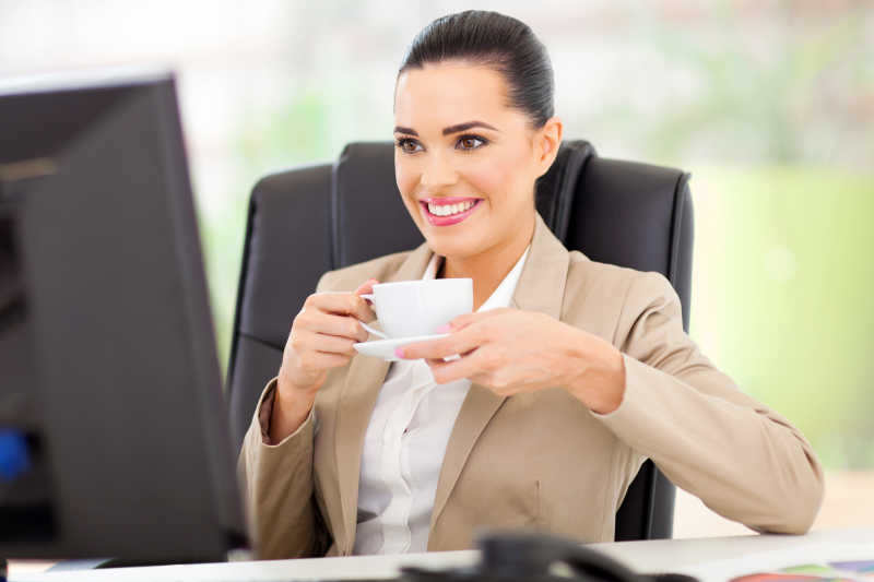 坐在电脑桌前喝茶的女商人