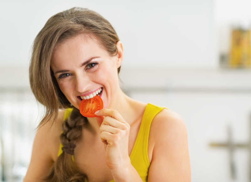 快乐的年轻女子正在吃红蕃茄