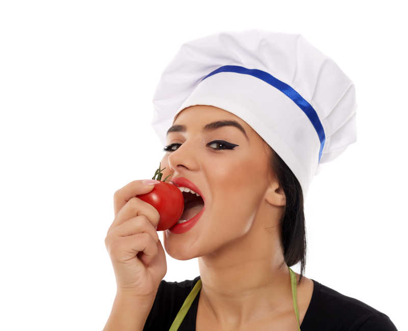 女厨师在吃新鲜的西红柿
