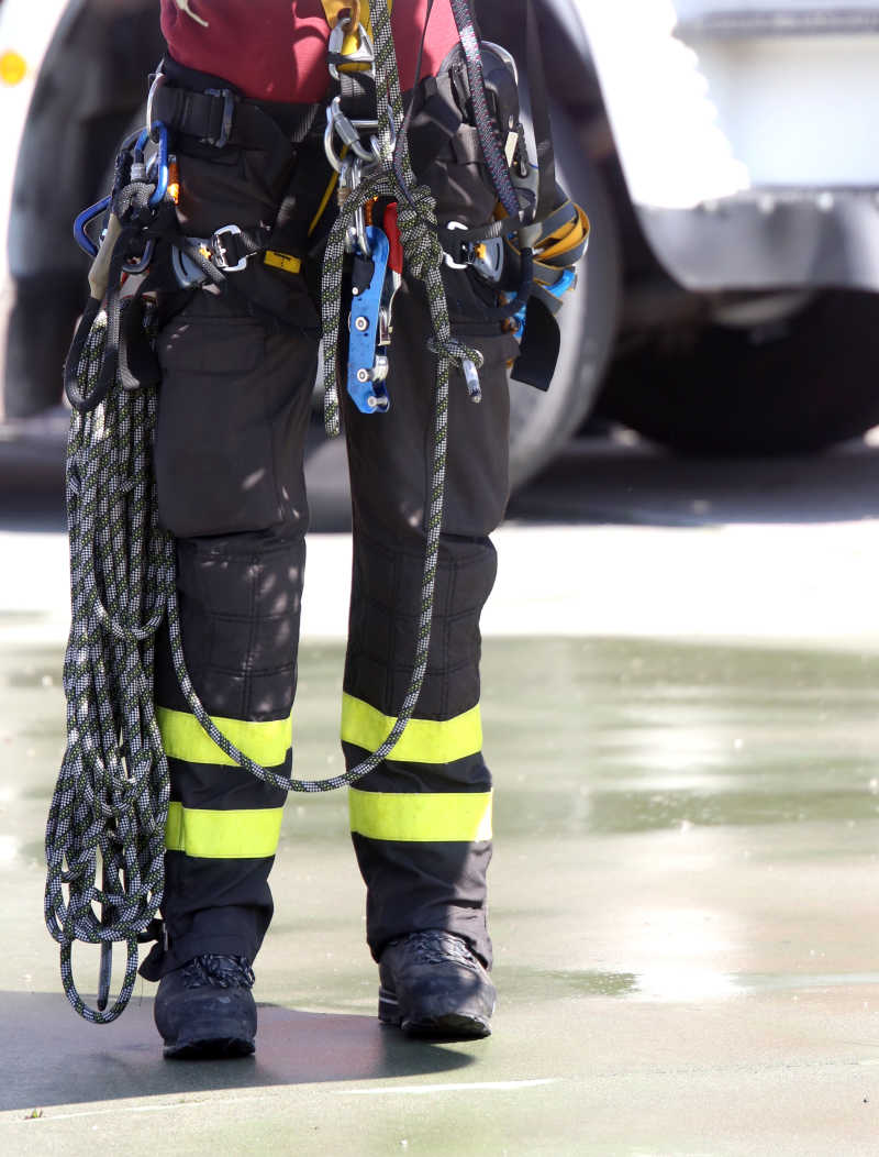 一个人穿着整齐的装备拿着登山用强力尼龙绳和工具