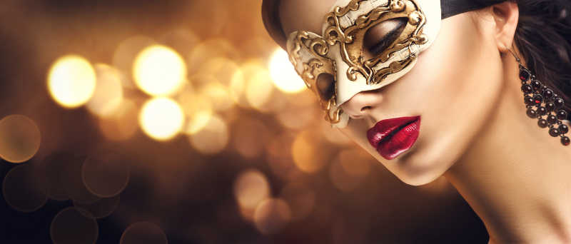 模糊灯光背景下带着金色面具画着红唇的性感女人