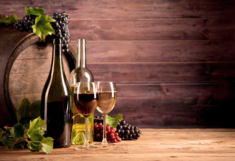 木桶旁边的葡萄和盛满葡萄酒的杯子特写