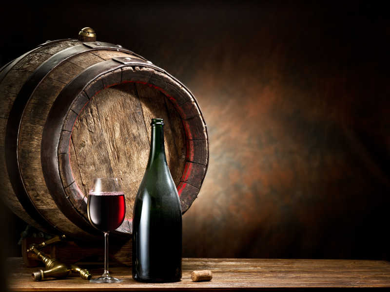 桌子上盛满葡萄酒的杯子瓶子和木桶