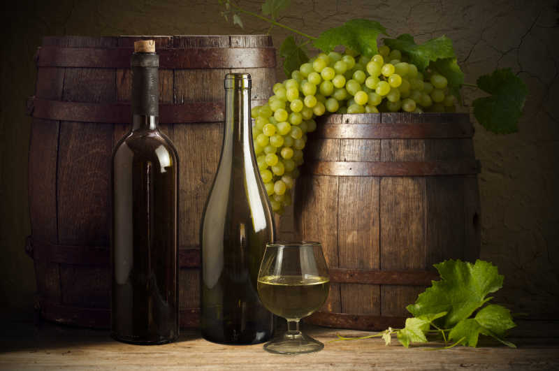 酒瓶红酒杯和放在木桶上的葡萄特写