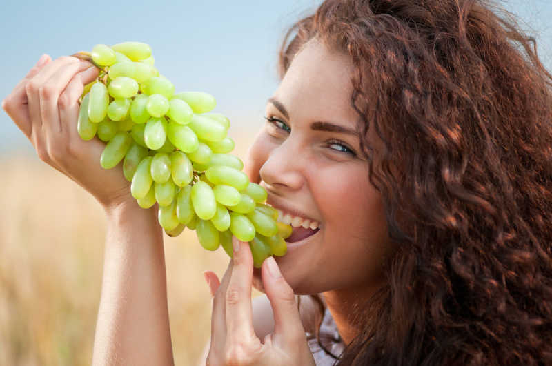 微笑的美女吃葡萄