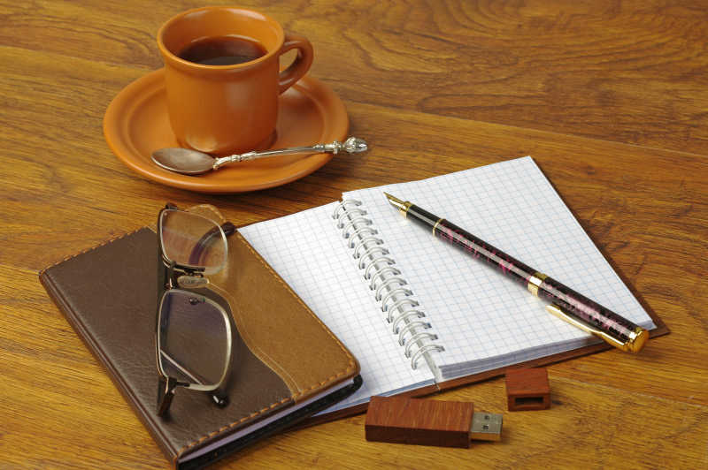 桌面上的笔记本眼睛咖啡和钢笔
