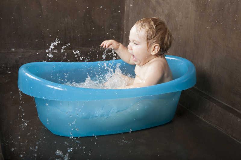 蓝色澡盆里玩耍的婴儿