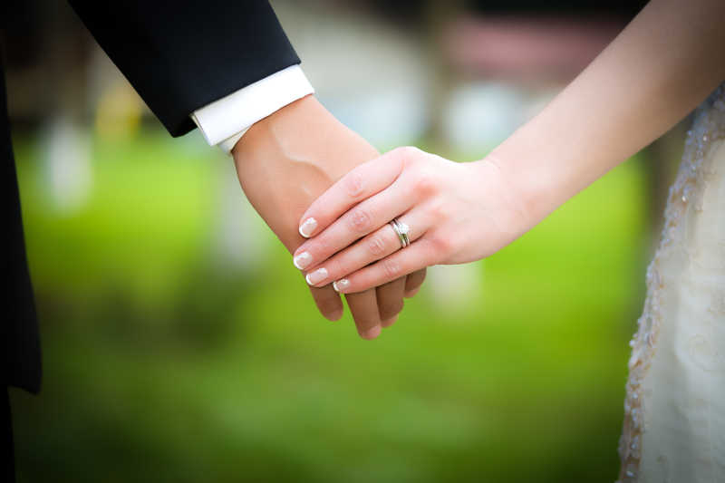 戴着戒指的新婚夫妇手牵手