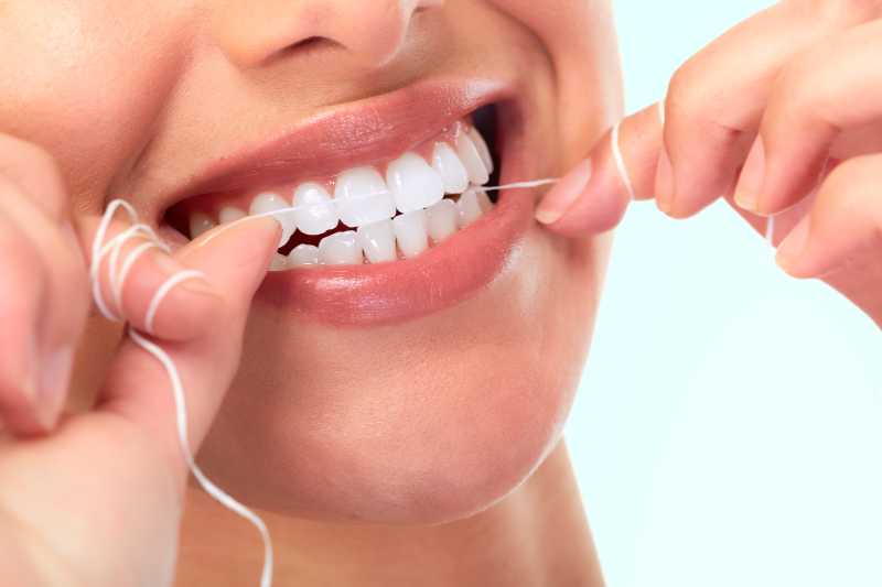 白色背景下使用牙线带来的健康的牙齿
