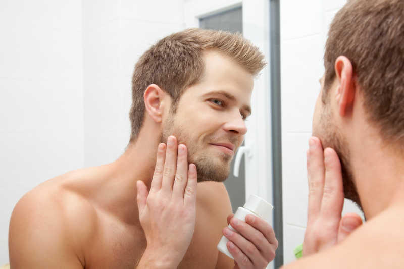 男人在镜子面前抚摸脸颊