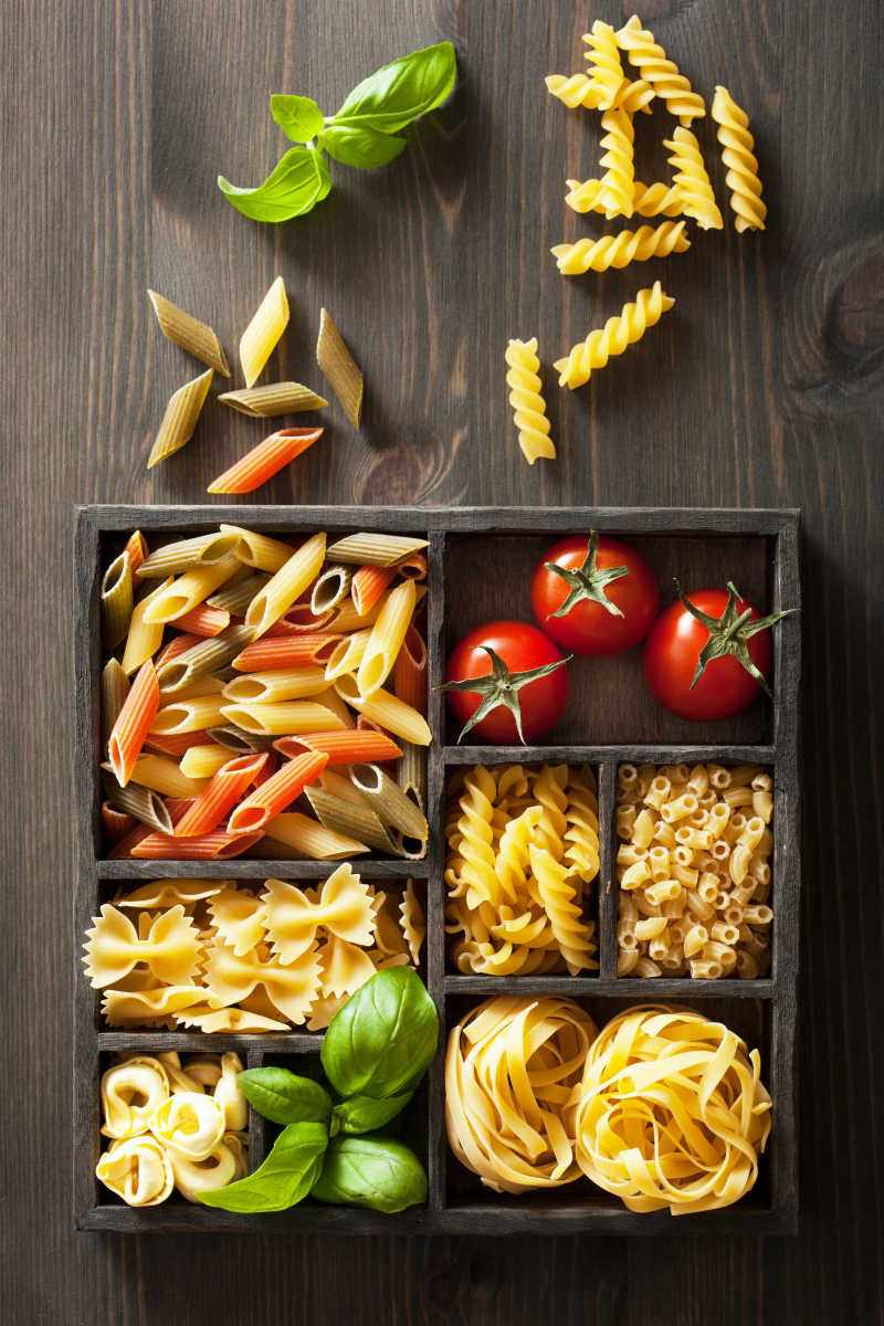 木桌上盒子里的意大利面和蔬菜
