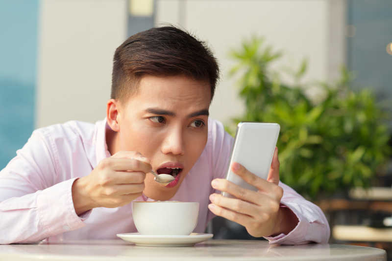 沉迷于手机的男人在吃饭