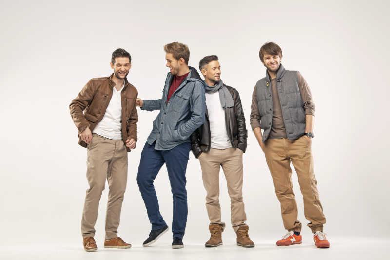 单色背景下四个穿着时尚的年轻男人