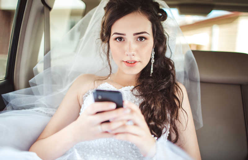 美女穿着婚纱拿着手机