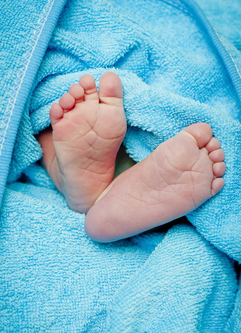 蓝色毛巾包裹里的婴儿的脚底板