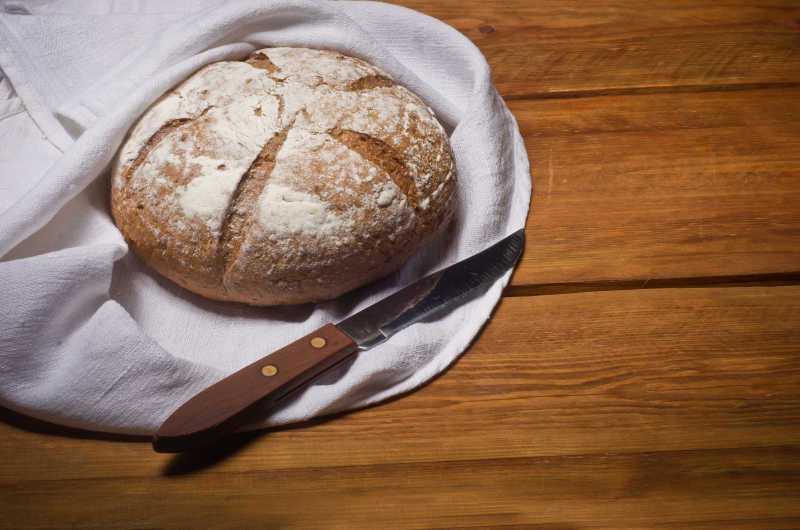 白面包布裹在木桌上的玫瑰色面包与面包刀