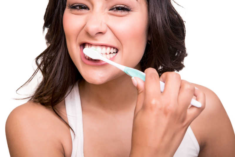 有着健康牙齿的微笑的年轻女子拿着牙刷