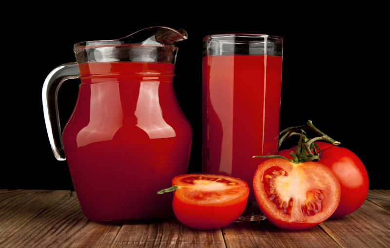 番茄汁和西红柿在黑色的背景上