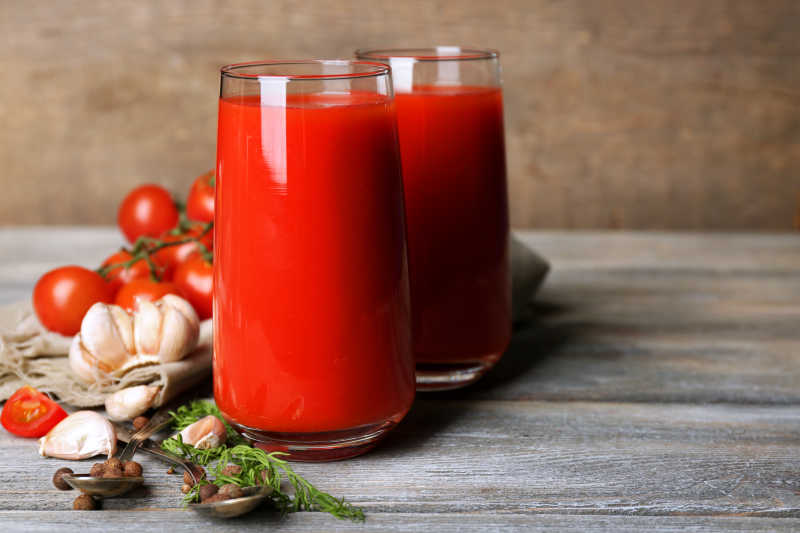美味的番茄汁和新鲜西红柿放在木桌上