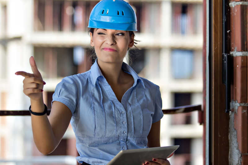 工地施工背景下带蓝帽子做表情的女建筑师