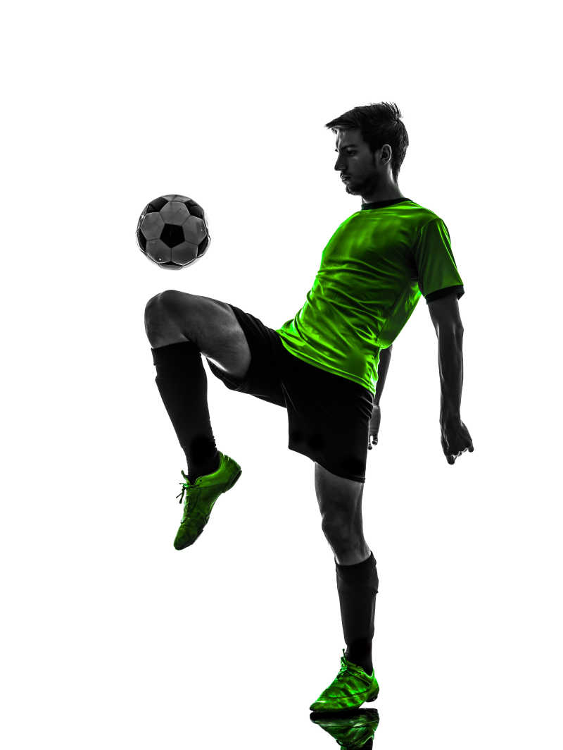 白色背景下穿绿色球服玩球的足球运动员