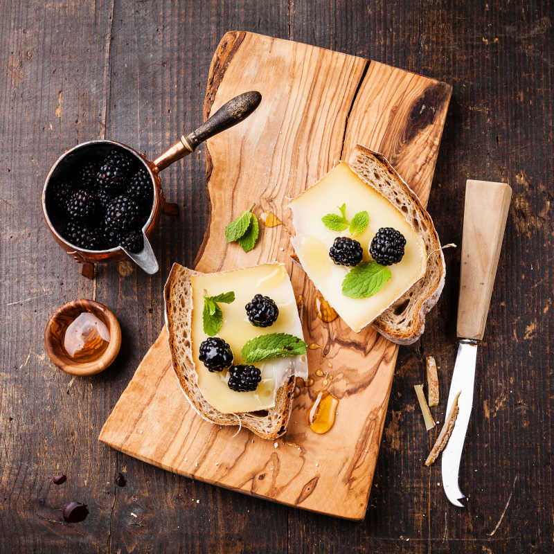 木质背景下的奶酪黑莓意大利面包三明治