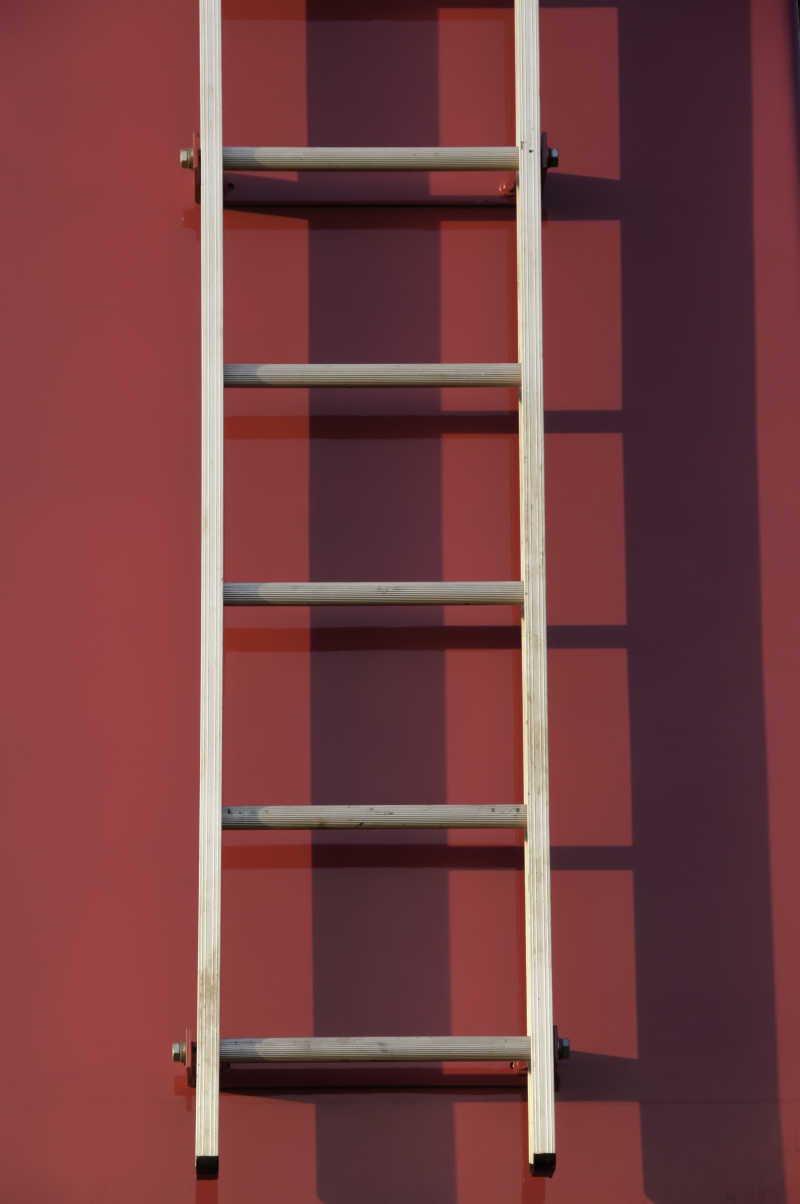 砖红色墙面上的木制梯子