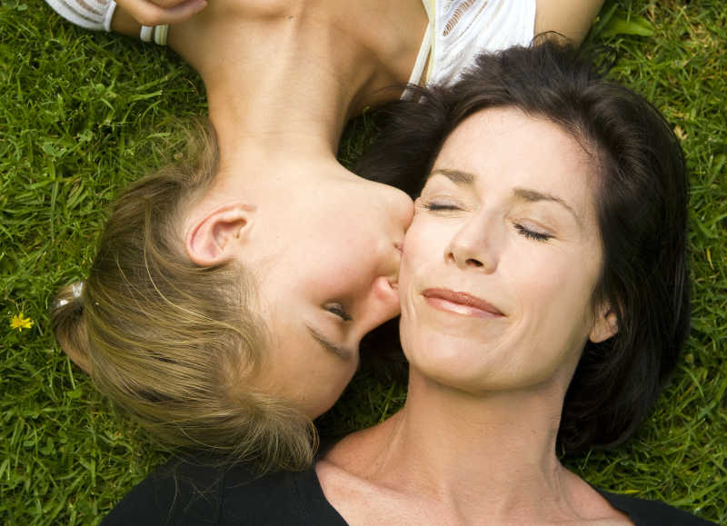 草地上亲吻母亲的女儿