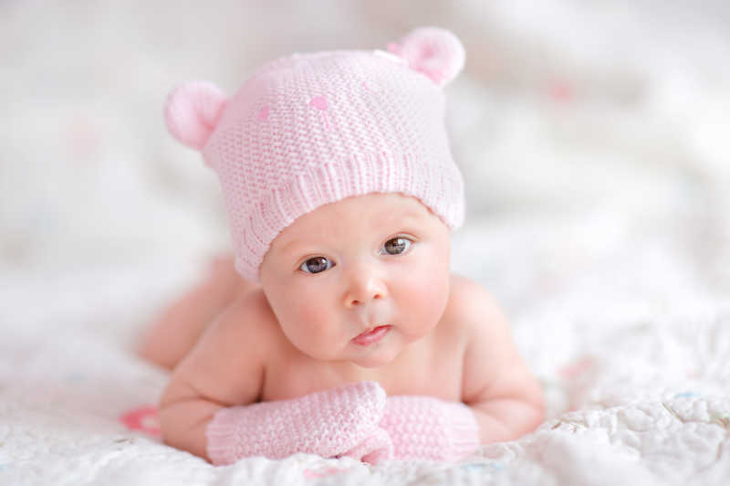趴着的戴着粉色针织帽的新生婴儿