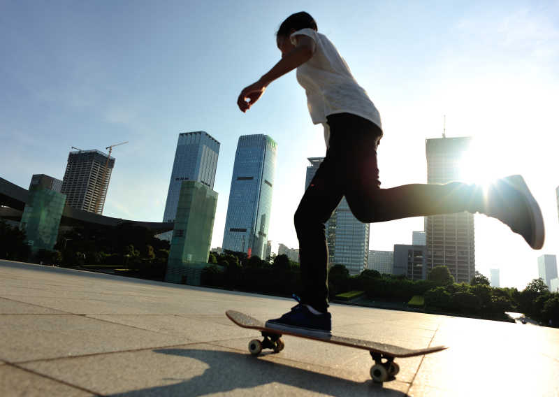 城市阳光下玩滑板的年轻男子
