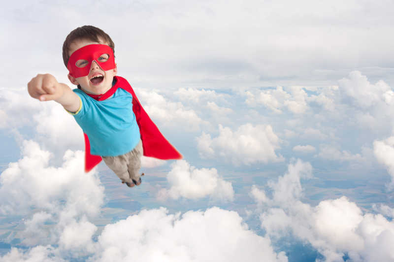 男孩穿着超人服装在云层上飞行