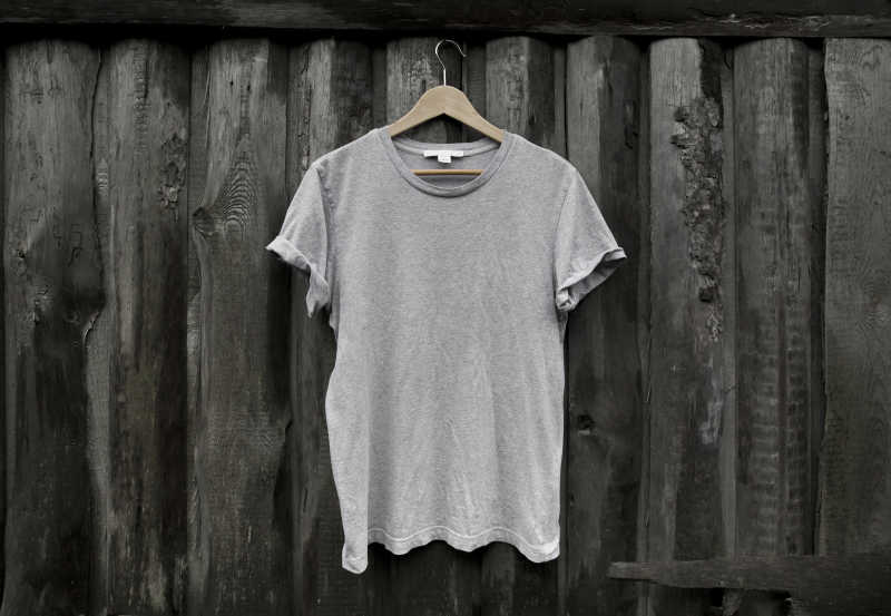 深色木墙上的灰色T恤衫
