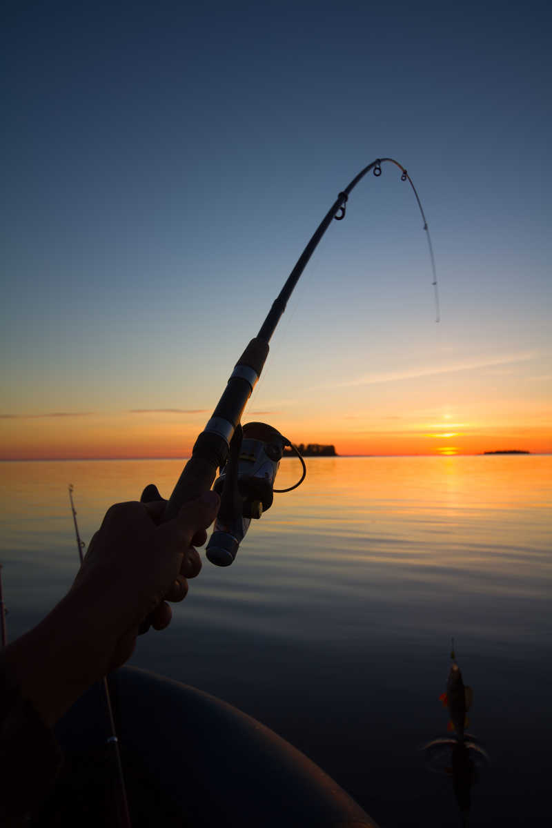 日落时手拿着钓鱼竿钓鱼