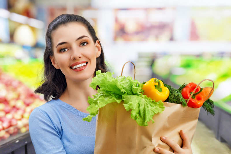 在超市中抱着蔬菜的女人